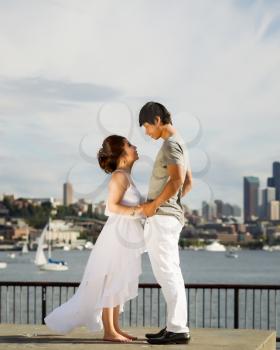 Vertical photo of young adult couple looking at each other with city of Seattle and harbor in Background