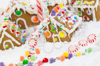 Closeup horizontal photo of Gingerbread houses surrounded by powered snow and candy cane candies 