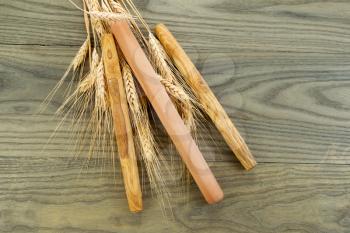Horizontal photo of three wooden bread rollers on aged white ash wood boards with dried wheat stalks 