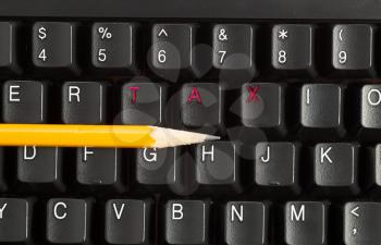 Horizontal photo of a yellow pencil on keyboard with the letters Tax in Red