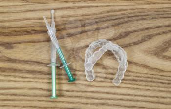 Overhead view of dental whitening trays and gel tubes on aged wood