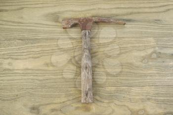 Horizontal photo of an old masonry hammer on aged wood