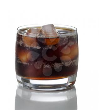 Glass filled with soda and ice on white with reflection