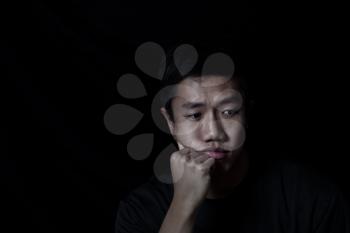 Young man depressed on black background 