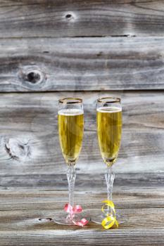 Vertical image of Golden champagne in elegant glasses on rustic wood with ribbons 