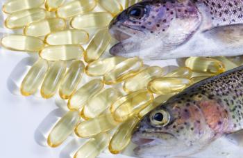 Image of trout, primary focus on second one, and fish oil pills on white