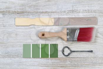 Paint brush with used stick, lid opener, and paint color choice on old white wooden boards