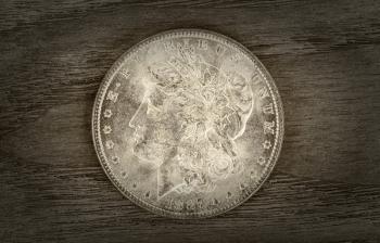 Vintage concept of a Silver Dollar in very good condition on aged wood. Slight vignette border around coin. 