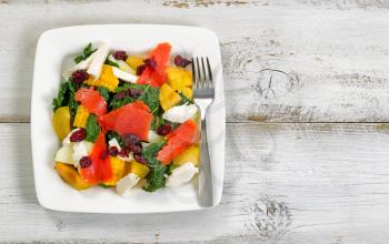 Top view image of a healthy fresh salad on plate with rustic white wooden boards underneath. 
