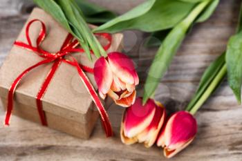 Boxed gift and flowers on stressed wood background