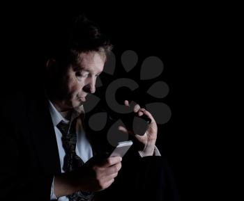 Stressed business man on cell phone while drinking a beer.  Dark background with light on subject.  