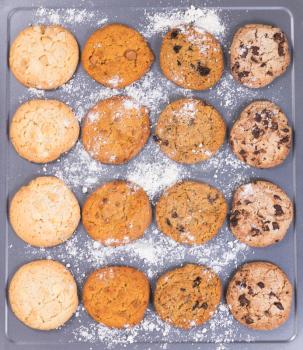 Top view of a variety of freshly baked cookies with flour on baking sheet