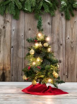 Christmas Tree decoration on rustic wooden boards with evergreen branches in background 