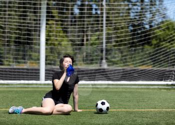 Teen age girl gulping down water during a hot day on the soccer field 