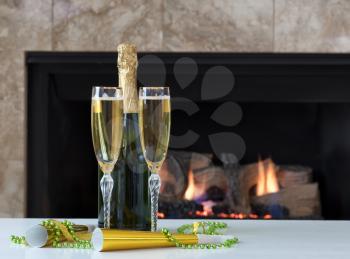 Happy New Year Celebration with golden champagne and glowing fireplace in background