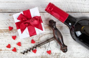Valentines gift with red wine and corkscrew opener on rustic white wood in flat lay view