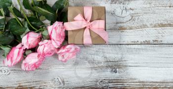 Half a dozen pink roses and gift box on rustic white wood in flat lay view