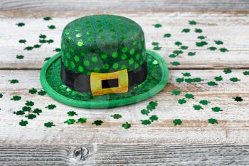 St Patrick day good luck hat with shiny clovers on rustic white wooden boards in close up view 