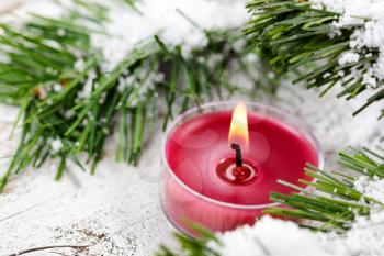 Select focus of glowing candle for Christmas holiday with evergreen and snow 