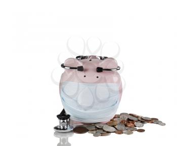 Piggy bank with medical mask, coins and stethoscope. Financial crisis concept. Isolated on white with reflection. 