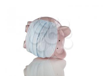 Tipped over piggy bank with medical mask on. Financial crisis concept. Isolated on white with reflection. 