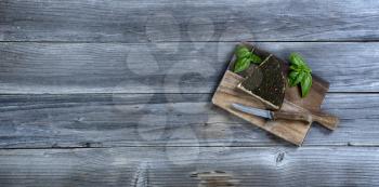 Fresh cheese wedge with basil leaves on rustic wood with copy space available 