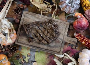 Freshly grilled steak with seasonal autumn decorations on table