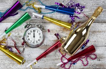 Closeup in filled format showing clock striking midnight for happy New Year concept with golden champagne and other party decorations 