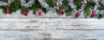 Border of Evergreen branches with tinsel and burning red candle decorations for Christmas or New Year holiday background 