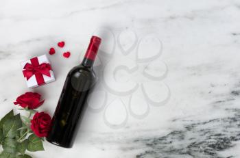 Happy Valentines Day with lovely rose flowers and red wine bottle plus giftbox on natural marble stone 