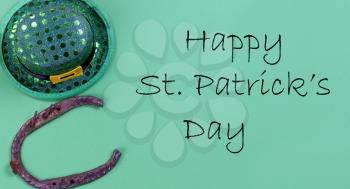 St Patricks day Irish good luck horse shoe and elf hat on a bright green paper background with copy space plus text message