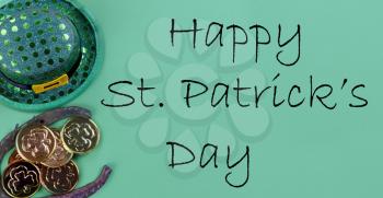 St Patricks day holiday celebration with Irish elf hat, horse shoe and gold coins on a green paper background with copy space plus text message