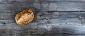 Top view of homemade full sourdough loaf of bread on weathered wooden planks 