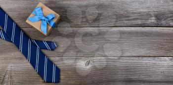 Fathers day concept with blue dress tie and gift box on rustic wooden background in flat lay format
