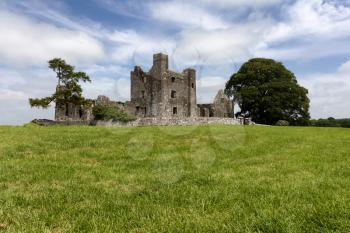 Small old castle in the middle of a grassy field in Ireland   