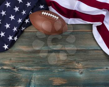 United States flag with American football on faded blue wooden planks for sport concept 