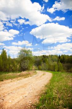 Country road under blue sky with white clouds, vertical shot