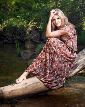 Beautiful girl in the national dress stand in the  forest nearthe  river