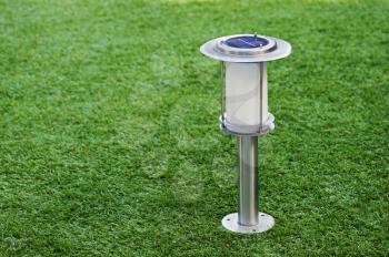 Solar-powered lamp on green grass background. Selective focus.