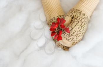 Woman hands in light teal knitted mittens are holding red heart on snow background. Winter, Valentines and Christmas concept.