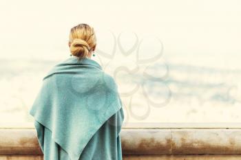 Back view of a woman with tied blond hair looking at the nature background during a nice sunny morning. Photo with retro filter effect.
