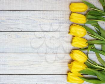 Fresh yellow tulips on wooden background. Holiday background. Top view.