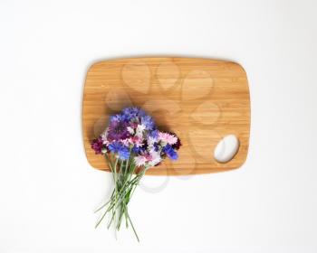 Wooden cutting board with decoration of flowers on white background. Overhead view. Flat lay.