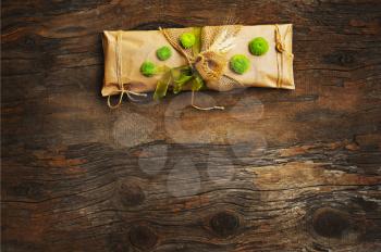 Handmade gift decorated with natural flowers, ears of wheat and elements on dark wooden background.
