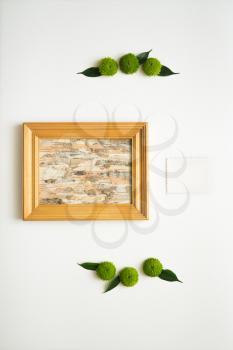 Wooden frame with collage of birch bark and paper with decoration of chrysanthemum flowers and ficus leaves on white background. Overhead view. Flat lay.