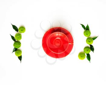 Red cup for coffee or tea with decoration of chrysanthemum flowers and ficus leaves on white background. Overhead view. Flat lay.