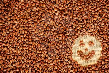 Face coffee frame made of coffee beans on burlap texture. 