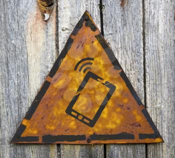 Royalty Free Photo of a Smartphone on a Rusty Sign Hanging on a Wooden Wall