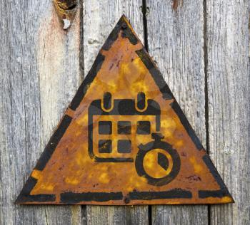 Royalty Free Photo of a Calendar and Stopwatch on a Rusty Sign Against a Wooden Wall