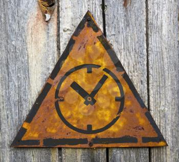 Royalty Free Photo of a Clock on a Rusty Sign Against a Wooden Wall